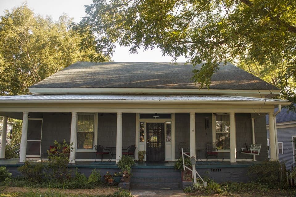 Front view of house.  Stairwell to apartments on left side of front porch.