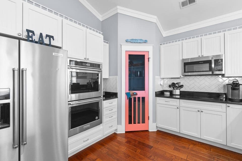 Your gourmet kitchen features stainless steel appliances and a charming coral pantry door that adds personality to this elegant cooking space.