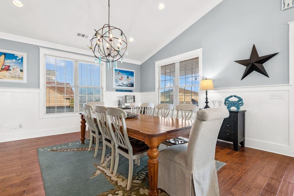 Gather around this elegant farmhouse table for memorable meals together, surrounded by coastal charm and warm lighting.