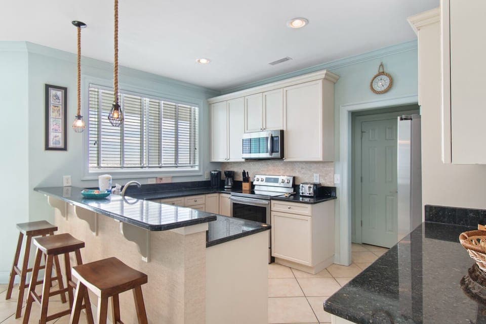 Your coastal-inspired kitchen awaits with granite counters, breakfast bar seating, and full appliances for home-cooked meals during your stay.