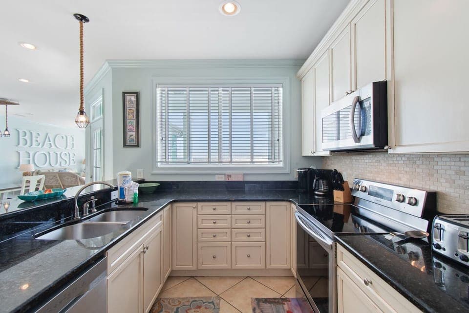 Your fully equipped coastal kitchen features granite counters and stainless appliances, perfect for preparing meals with charming beach house touches.