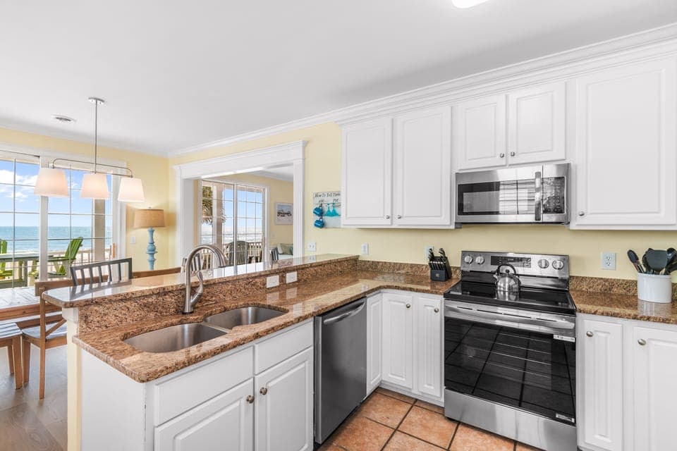 Your fully-equipped kitchen opens to ocean views, featuring granite counters, stainless appliances, and everything you need for beachside dining.