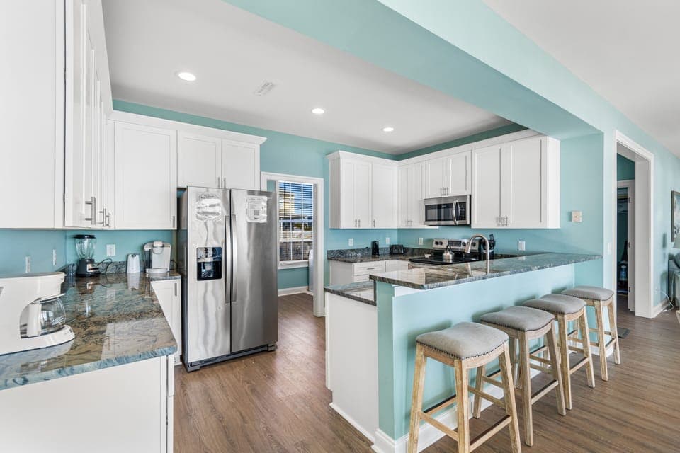 Your spacious kitchen invites culinary adventures with granite counters, stainless appliances, and coastal-inspired turquoise walls that create a refreshing, beachy atmosphere.
