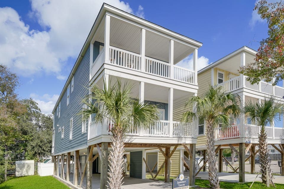 Modern beach house with elevated design, covered parking, and tropical palm landscaping creates an inviting coastal retreat.