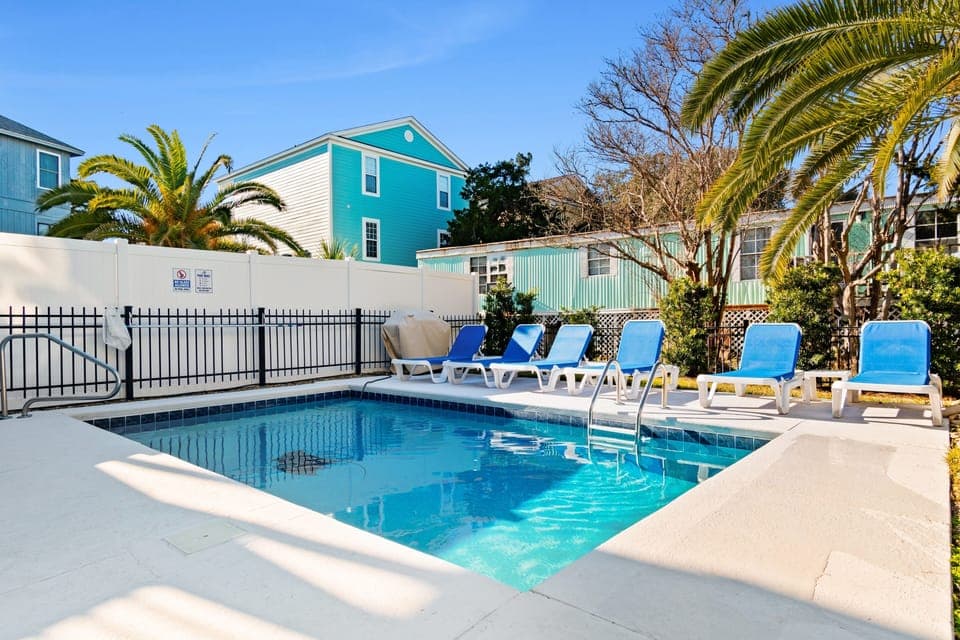 Dive into your private tropical oasis with crystal-clear pool waters, comfortable lounge chairs, and swaying palm trees creating the perfect vacation escape.