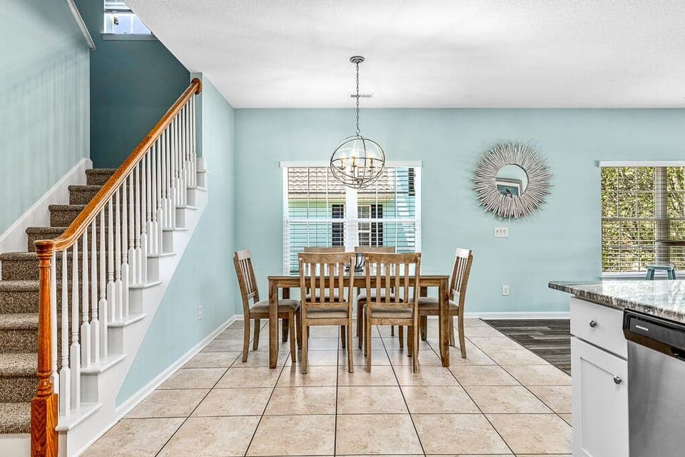 Your bright dining space welcomes memorable meals with natural light streaming through windows and a stylish chandelier overhead.