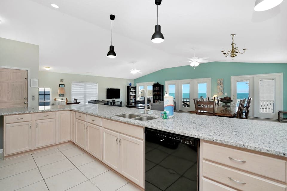 Your spacious kitchen flows seamlessly into the living area, where ocean views through expansive windows create the perfect backdrop for cooking and entertaining.