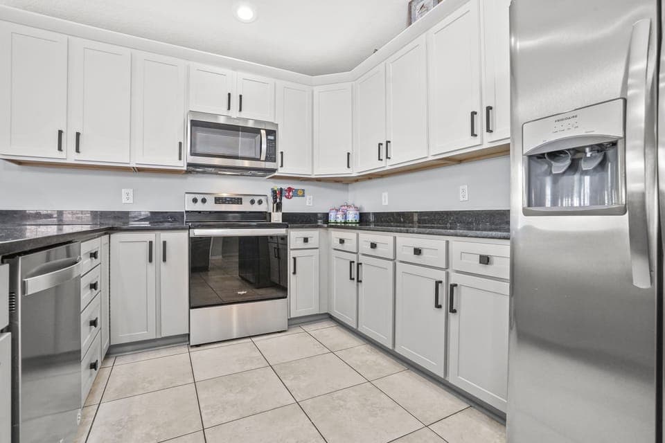 Your fully equipped kitchen features sleek white cabinets, granite countertops, and modern stainless steel appliances for effortless home-style cooking.