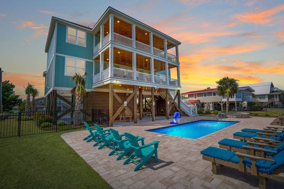Coastal beach house featuring private pool, spacious multi-level balconies, and vibrant turquoise seating for memorable sunset evenings.