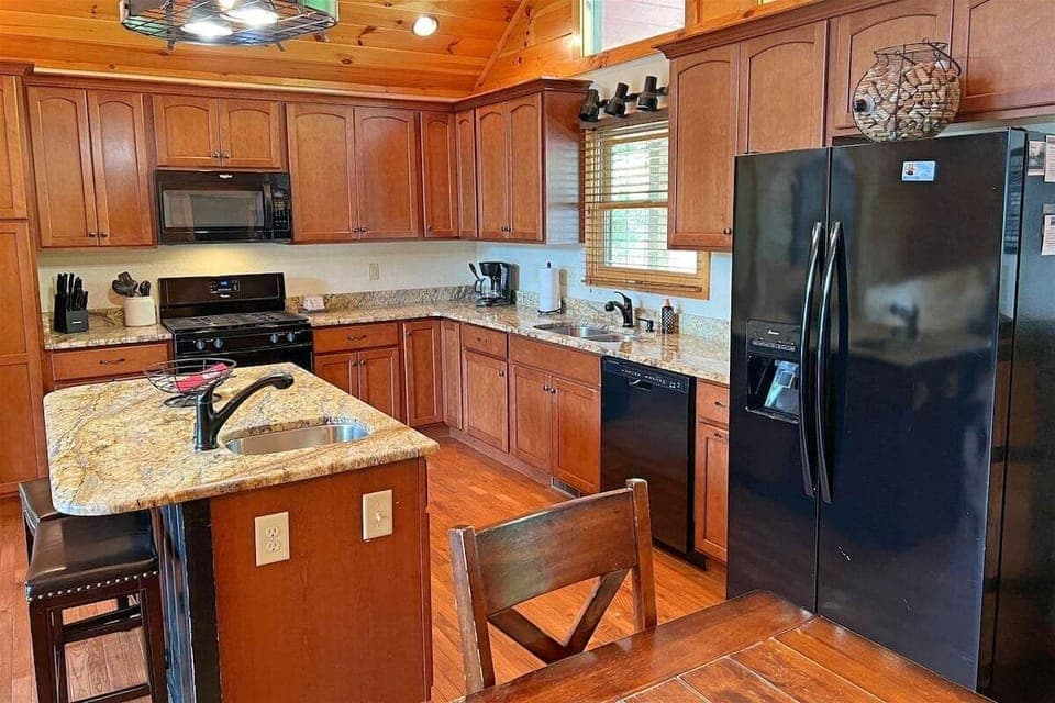 A spacious kitchen with granite countertops, modern appliances, and a center island makes meal prep easy at Smoky Mountain High.