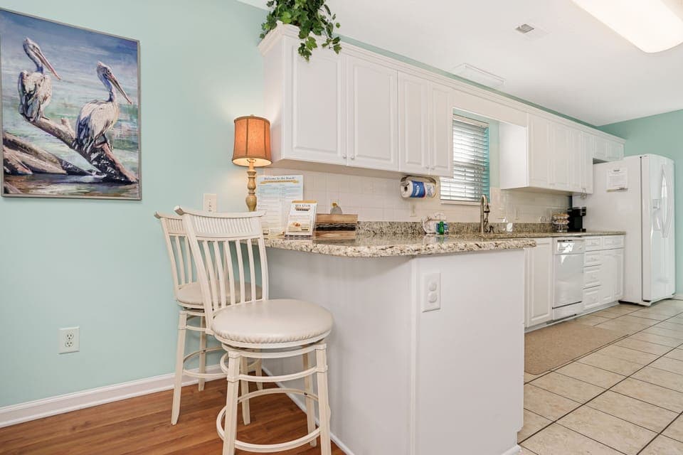 Your bright coastal kitchen features granite counters and breakfast bar seating, perfect for morning coffee or casual meals.