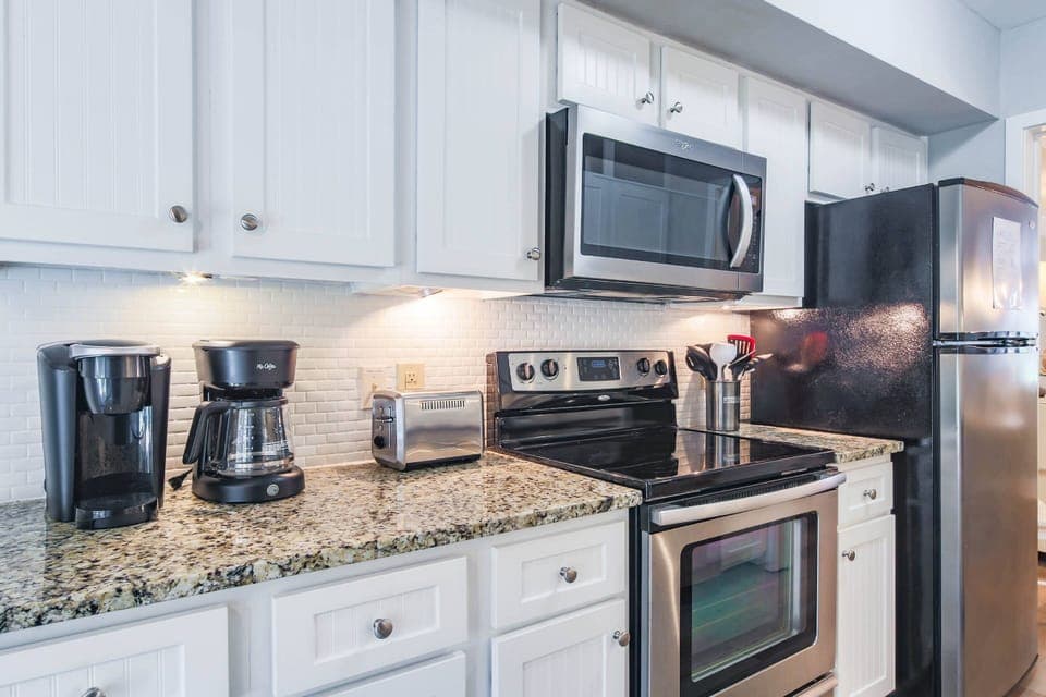 The kitchen features a refrigerator, electric range, microwave, toaster, drip coffee maker and keurig.