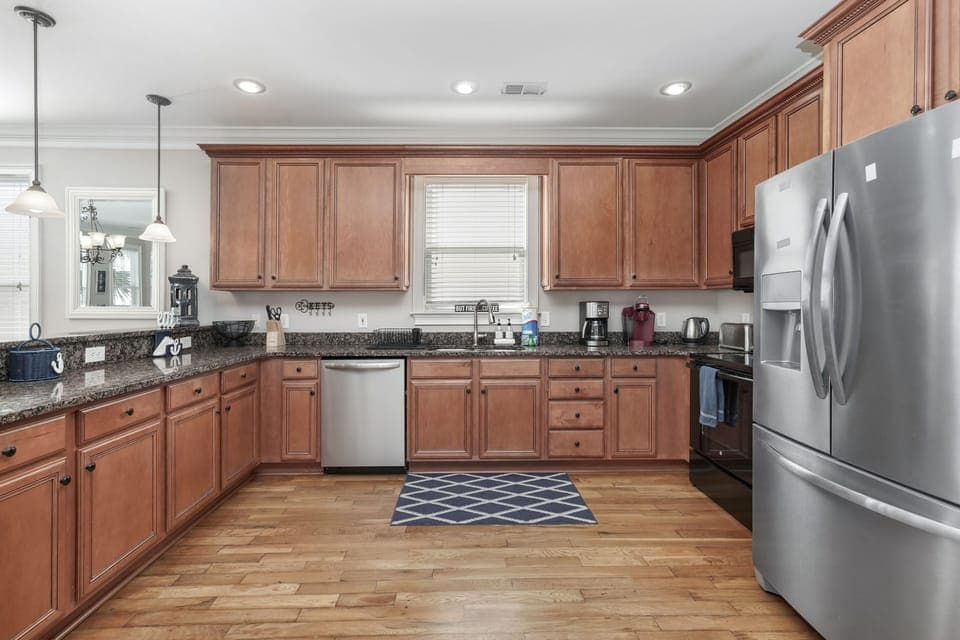 Your fully equipped kitchen features warm wood cabinetry, granite countertops, and modern stainless steel appliances - perfect for preparing meals during your stay.