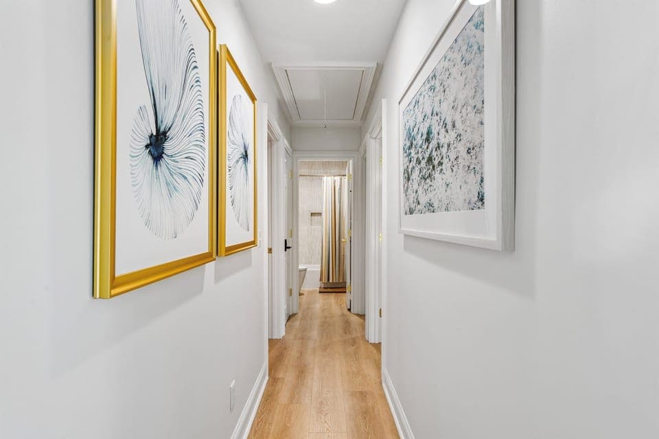 Hallway featuring coastal touches leading to 3 bedrooms and hall bath