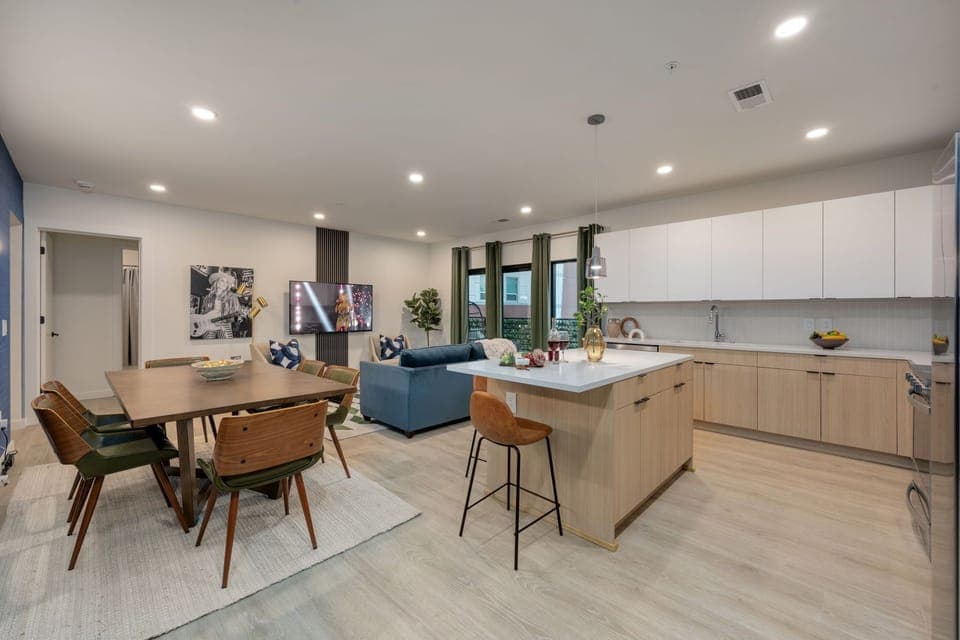 Spacious modern open-concept floor plan featuring the fully equipped kitchen, dining area, and designer furnished living room.