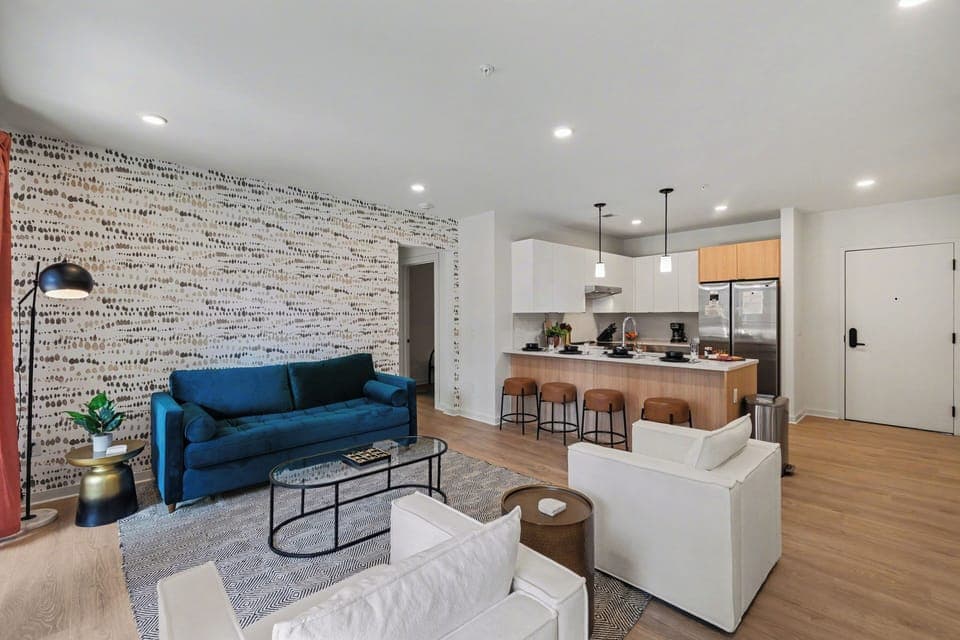 Bright open living space featuring smart flat-screen TV, designer furnishings, and patio entrance with pool view.