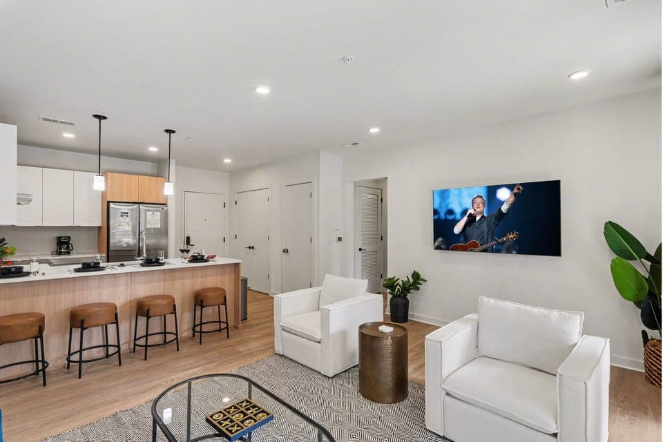 Bright open living space featuring smart flat-screen TV, designer furnishings, and patio entrance with pool view.