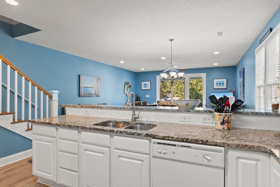 Your gourmet kitchen welcomes with granite counters, stainless appliances, and cheerful blue walls—perfect for morning coffee or preparing memorable meals.
