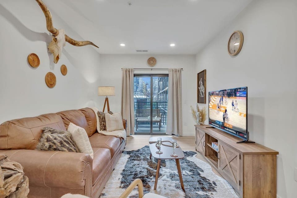 Warm and inviting living space featuring a flat-screen smart TV and designer furnishings with access to the private balcony.
