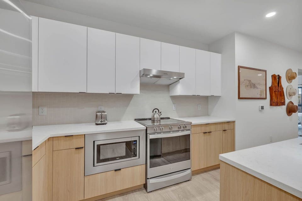 Fully equipped modern kitchen stocked with all culinary essentials and featuring brand new stainless steel appliances with an island offering bar seating.