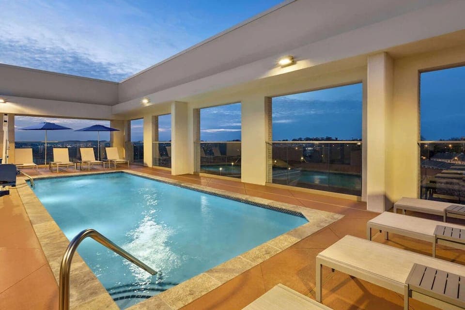 Unwind at dusk with a glowing rooftop pool and skyline.