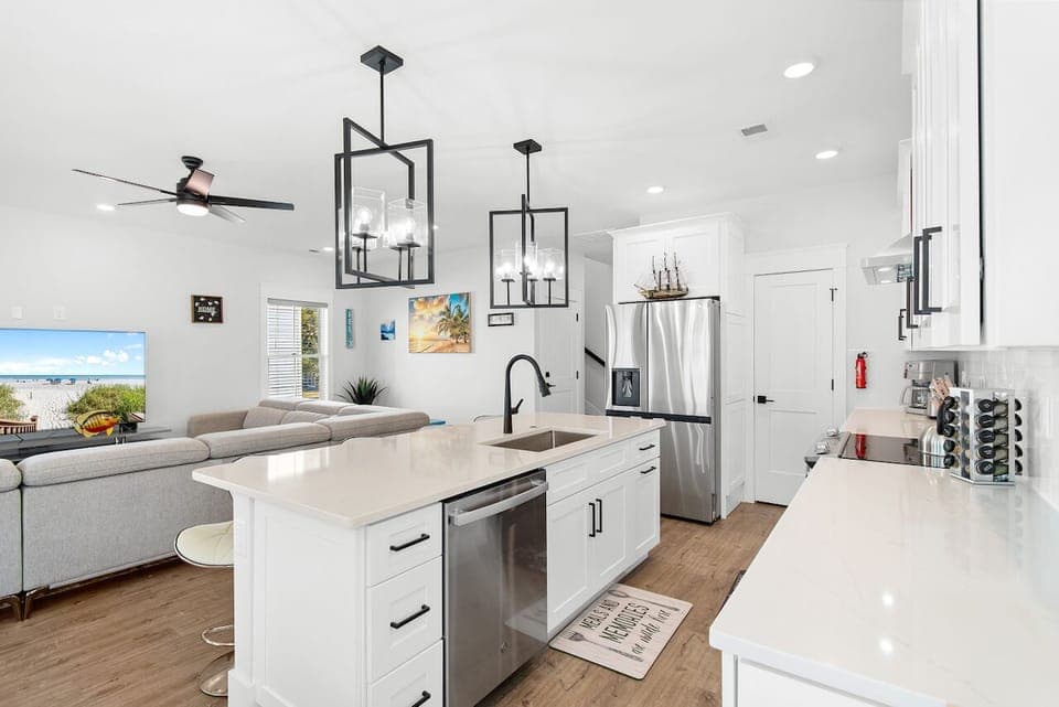 Your sleek, modern kitchen features pristine white countertops and stainless steel appliances, perfect for preparing meals while gazing at the ocean view.