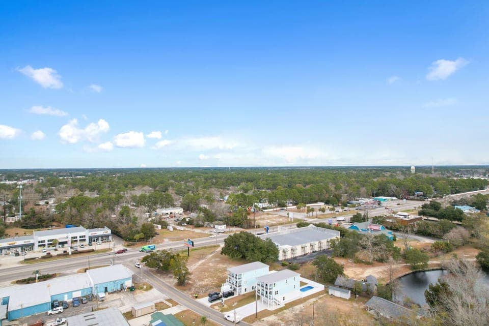 Aerial view of the property's peaceful neighborhood, surrounded by lush trees and open spaces with convenient access to local amenities.