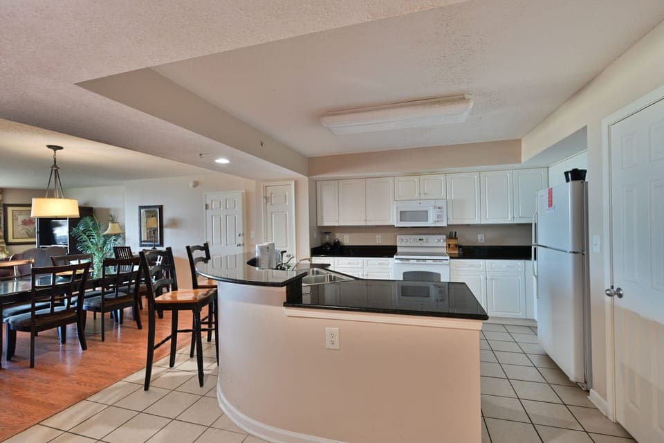 Bright eat-in kitchen with stools and tile flooring