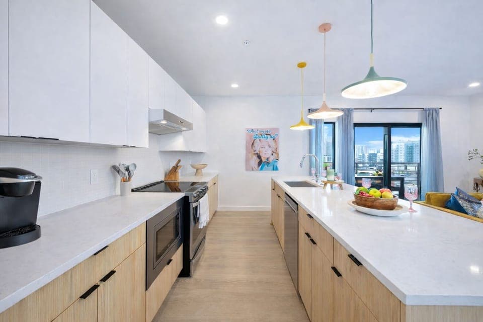 Fully equipped kitchen stocked with all culinary essentials and featuring brand-new stainless-steel appliances and a large kitchen island offering bar seating.