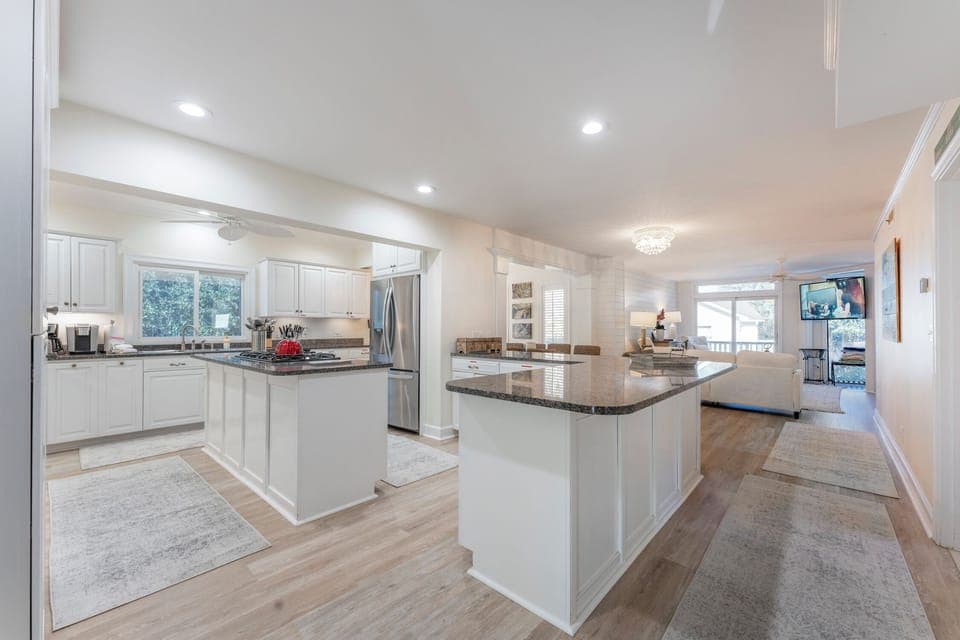 A modern kitchen with white cabinets, a built-in oven, a gas stove, and a large granite island.