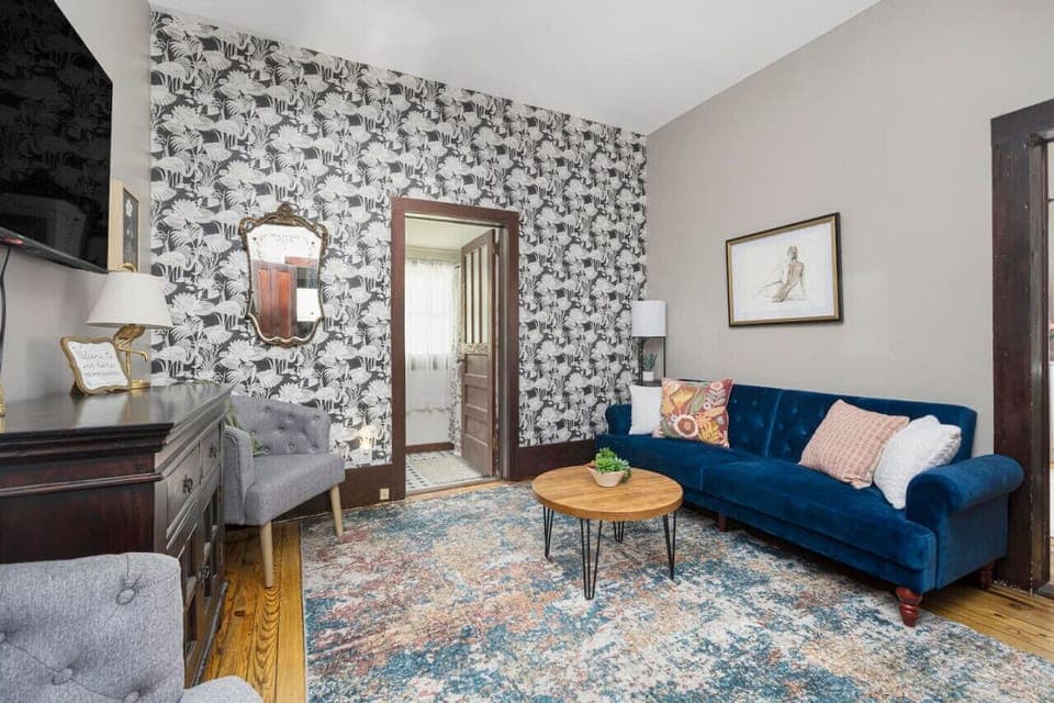 The living room's vibrant wallpaper adds a pop of charm, complemented by thoughtfully curated decor.