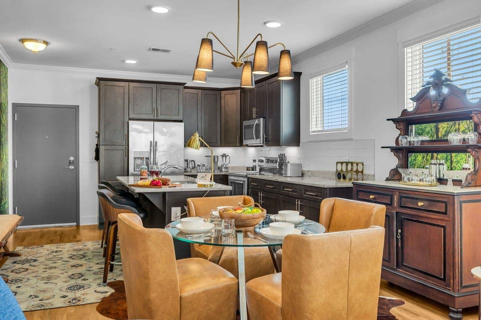 The dining area features a table for four and a hutch with cocktail-making utensils and drinkware, perfect for unwinding after a day of exploring. Overlooking the fully equipped kitchen.