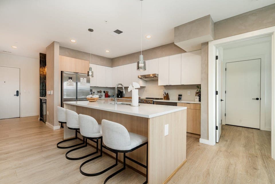 Fully equipped modern kitchen featuring culinary essentials, stainless steel appliances, and island bar seating.