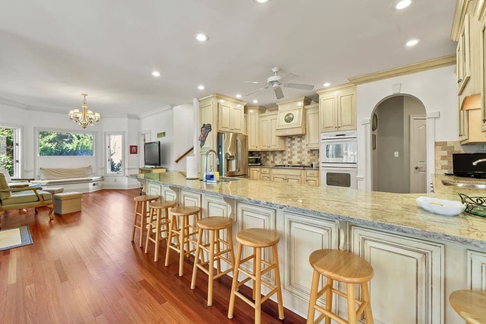 Spacious white kitchen with over-sized counter with overflow seating for 8. 