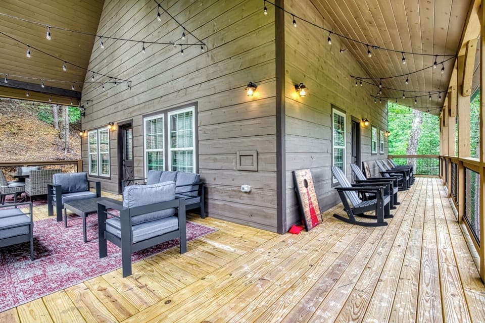 Covered deck with cushioned seating, outside dining area, and rocking chairs
