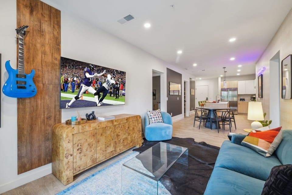 Warm and stylish living room featuring a large Smart TV, elegant furnishings, and a spacious balcony.
