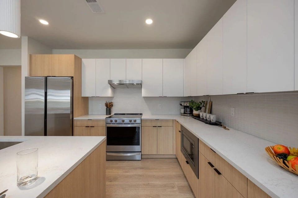 Unit 1: Fully equipped modern kitchen stocked with culinary essentials featuring stainless steel appliances with island bar seating.