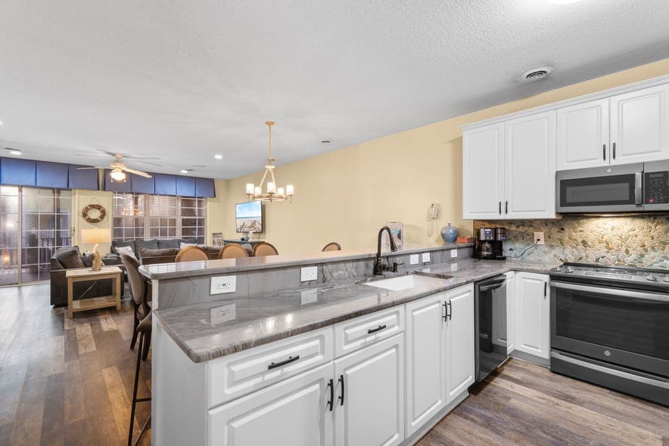 Your spacious open kitchen flows seamlessly into the living area, featuring granite counters, modern appliances, and warm lighting perfect for cooking and gathering.