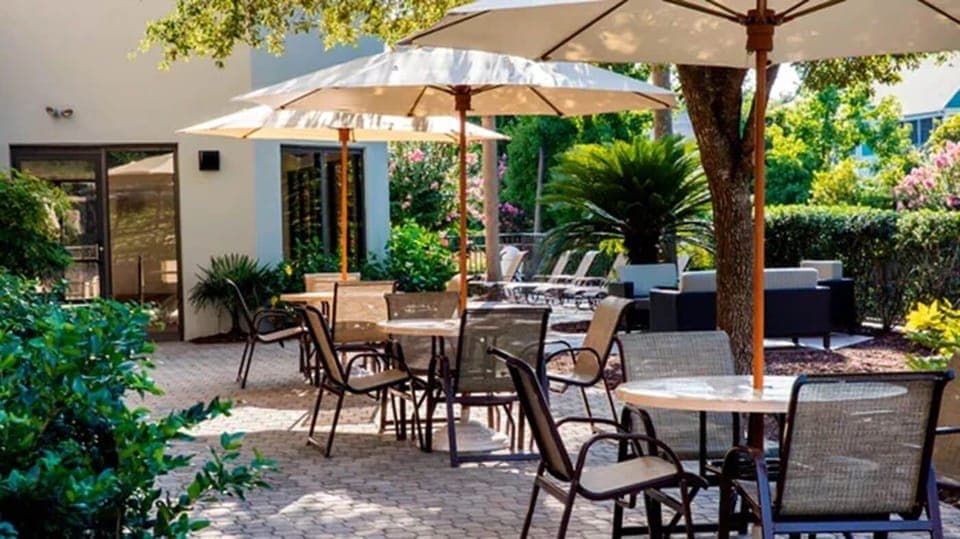 Enjoy morning coffee outdoors beneath shaded, breezy umbrellas.