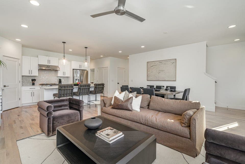 Relax in the cozy living room with ample seating, a flat-screen TV, and natural light pouring through large windows.