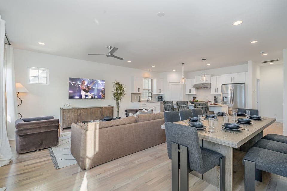 Relax in the cozy living room with ample seating, a flat-screen TV, and natural light pouring through large windows.