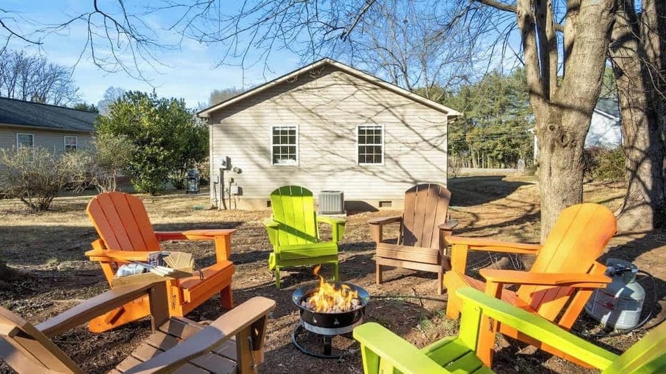 Spacious backyard with colorful Adirondack chairs and a fire pit—ideal for cozy nights under the stars.