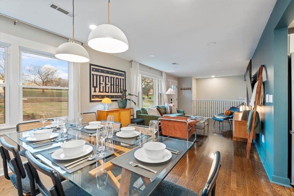 Dining area with glass table for eight, bold artwork & warm natural light.