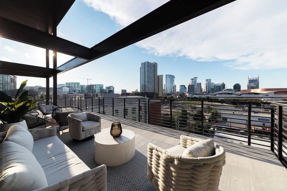 Stylish and inviting balcony with modern furnishings, lush greenery, and stunning city skyline views.