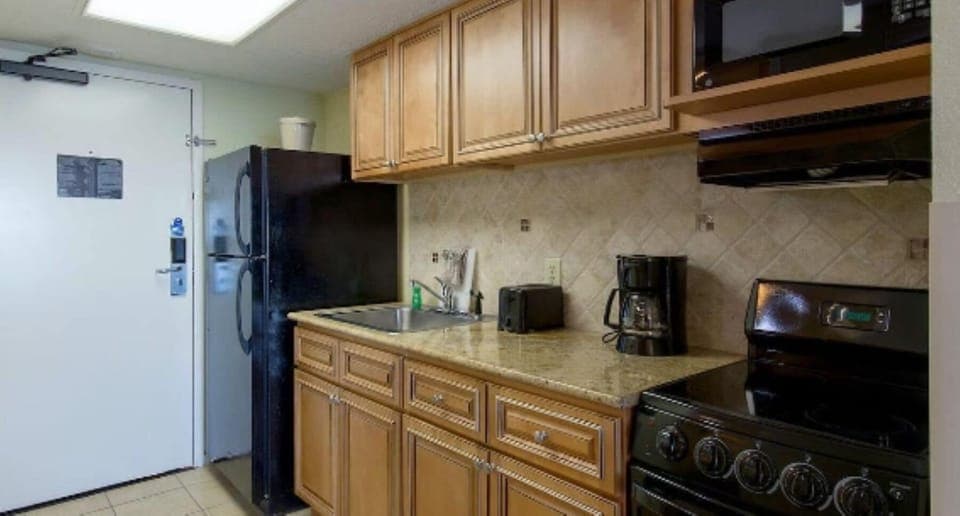 Modern kitchen with fridge, oven, microwave, coffee maker, and granite counters.
