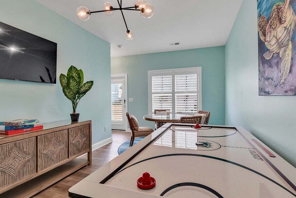 An alternate view of the game room with air hockey and a wall-mounted TV.