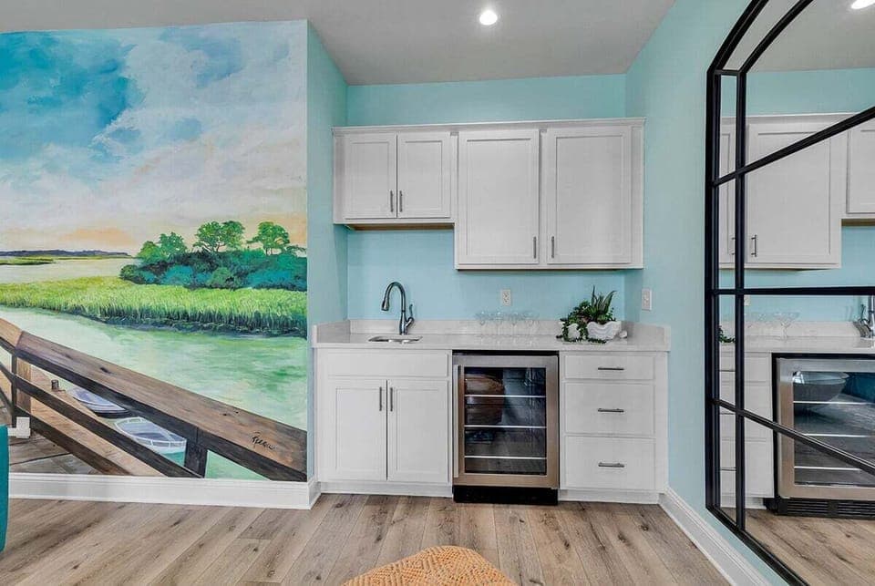 A built-in beverage area with sink and storage beneath mural artwork.