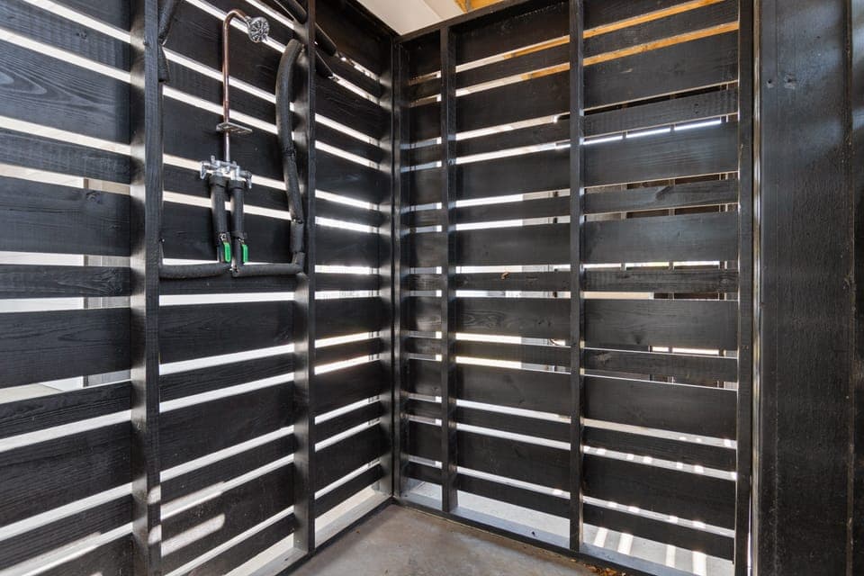 Rinse off in your private outdoor shower, where natural light filters through stylish wooden slats for a serene, spa-like experience.