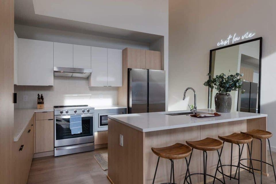 Stylish and functional tall ceiling kitchen with stainless steel appliances, full size mirror and natural wood accents.