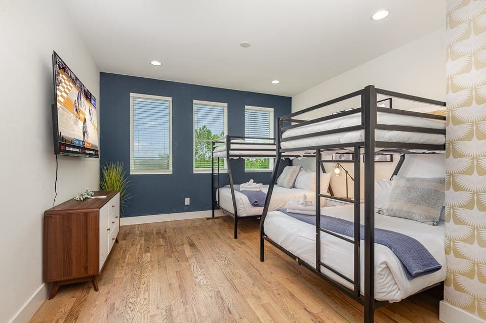 Unit 1: Additional Sleeping Arrangement featuring 2 Twin over Full Bunk Beds, Smart TV, Dresser, and Futon.
